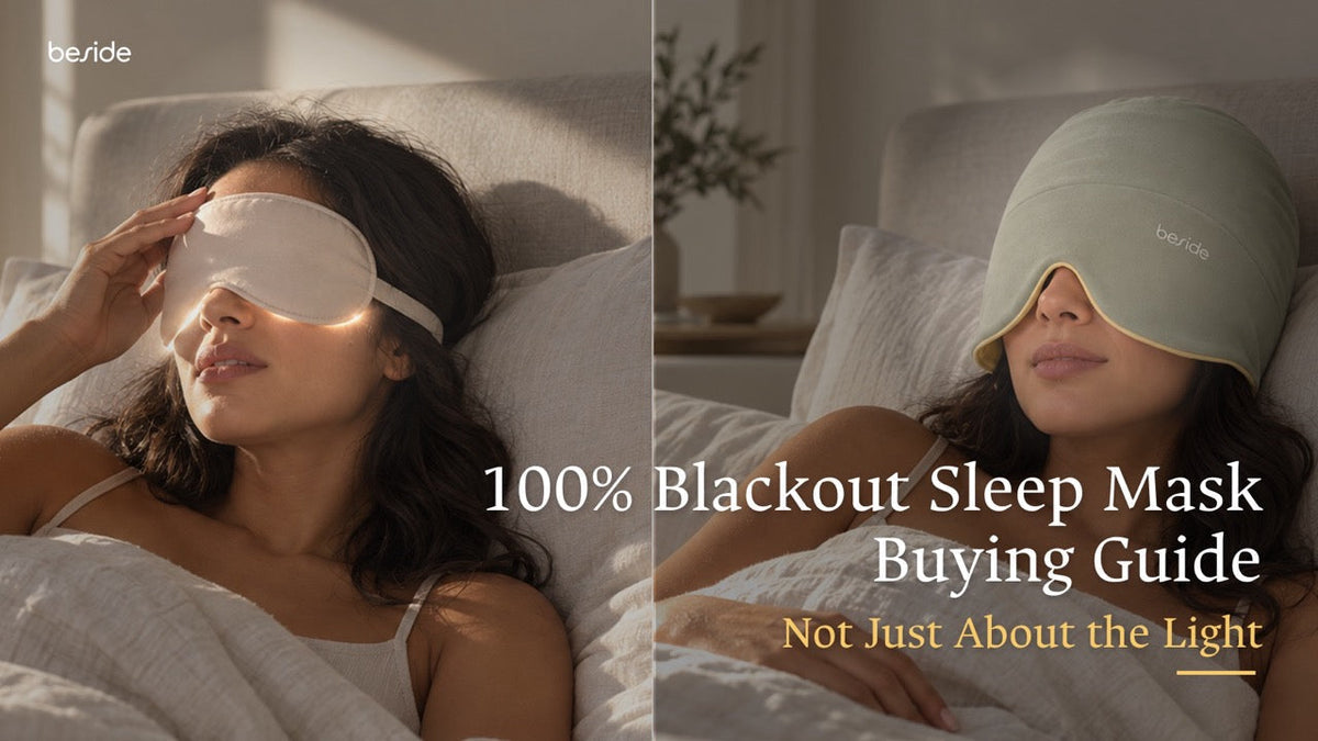 Woman lying in bed wearing two different blackout sleep masks, comparing standard silk mask and full‑coverage hood.