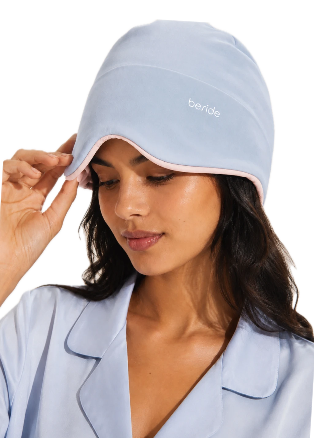 Woman adjusting a light blue Sleep Hood over her eyes.